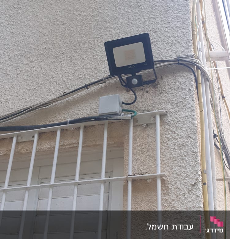 תאורת חוץ מותקנת על קיר עם חוטי חשמל